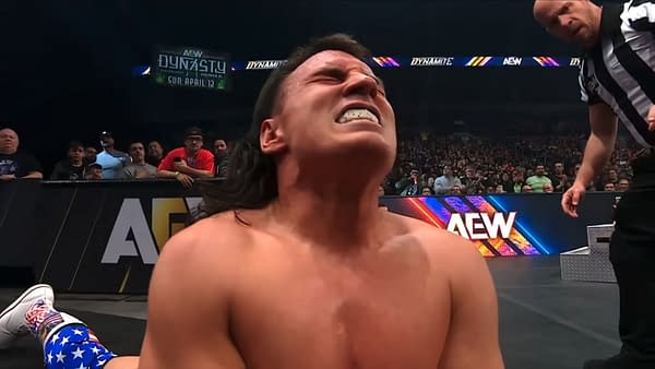 Speedball Mike Bailey is seen writhing in agony during a wrestling match against MJF on AEW Dynamite, with a referee observing nearby. The audience is visible in the background, reacting to the intense moment.