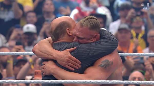 Two wrestlers embrace in a celebratory hug in the wrestling ring, surrounded by an enthusiastic crowd.