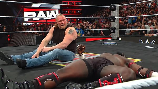 Brock Lesnar sits on the WWE Raw ring mat after a brutal attack, with Oba Femi lying motionless nearby and the crowd watching from behind the ropes.
