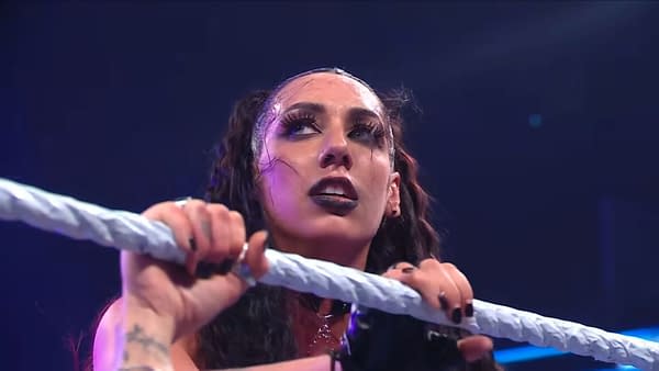 Jacy Jayne grips the ring ropes and looks up tensely during a WWE SmackDown match, reacting as Rhea Ripley's music hits after her win over Charlotte Flair.