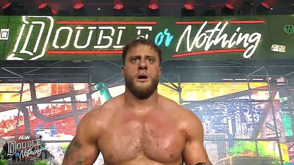 Kevin Knight stands shirtless in front of the AEW Double or Nothing stage, looking shocked after attacking Darby Allin. The wrestling arena backdrop reads