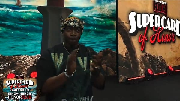 Prince Nana claps in front of a Ring of Honor Supercard of Honor backdrop during a wrestling segment about Swerve Strickland attacking Bandido. The scene emphasizes the ROH event branding and Nana's approval.