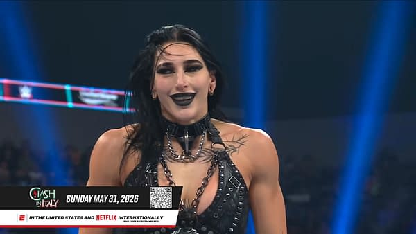 Rhea Ripley smiles in the WWE ring during Saturday Night's Main Event, wearing dark ring gear and black makeup. A