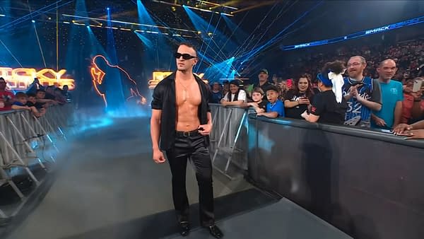 Ricky Saints stands on the WWE SmackDown entrance ramp in sunglasses and an open black shirt, making his debut before the crowd.