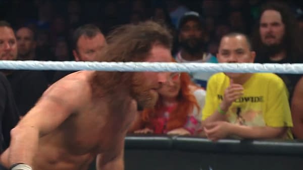 Sami Zayn crouches in the ring, charging up for a Helluva Kick during WWE Backlash while the crowd watches from behind the ropes.
