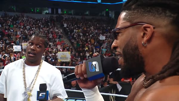 Trick Williams speaks with Lil Yachty in the ring on WWE SmackDown, with a packed arena crowd in the background.