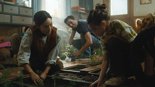 Greta Lee, Riley Chung, and Wagner Moura kneel together in The Last House, tending small plants indoors.