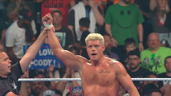 Cody Rhodes stands in the ring with his arm raised in victory after winning a number one contender match on WWE SmackDown. A referee lifts his hand as the crowd watches behind him.
