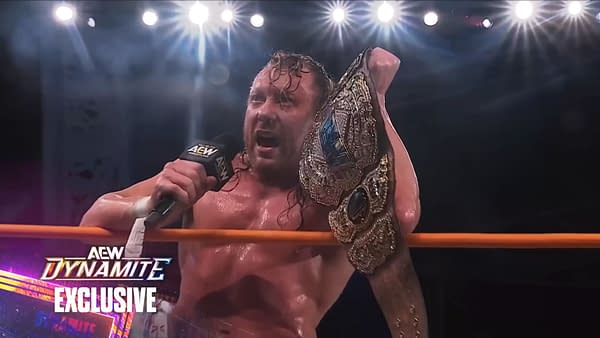 Kenny Omega, sweaty and triumphant, addresses the crowd in the AEW ring while holding the AEW World Championship after winning at Beach Break.