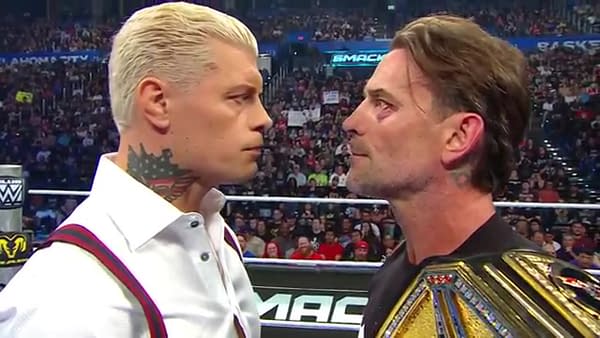A close-up shot from shoulders up of Cody Rhodes and WWE Champion CM Punk staring face-to-face in the middle of a wrestling ring on WWE SmackDown, the WWE Championship draped over the shoulder of Punk, who has a black eye.