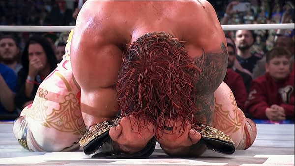 Will Ospreay kneels in the ring, clutching the AEW Men's World Championship belt after his title win at AEW All In London. His face is pressed into the mat in an emotional celebration.