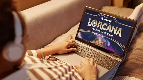 Someone playing the Disney Lorcana trading card game on a laptop while lying in bed at night.