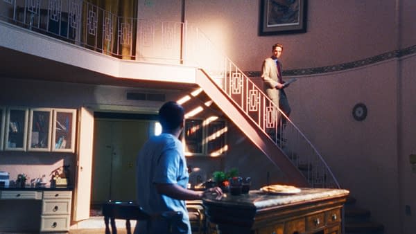 Two men stand in a sunlit, vintage-style home interior with a staircase and kitchen island, evoking a dramatic primetime scene.