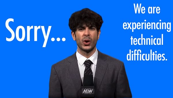 A man in a gray suit with a microphone in front of a bright blue background, AEW owner Tony Khan, apologizes and announces technical difficulties. The large text beside him says 'Sorry...' and 'We are experiencing technical difficulties.'