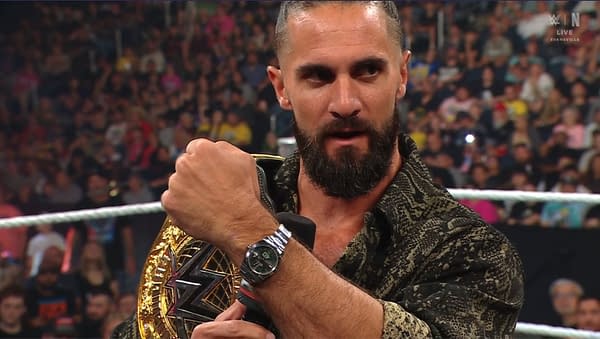 Seth Rollins shows off the WWE Championship belt while addressing the crowd on WWE Raw, wearing a stylish patterned shirt and a watch.