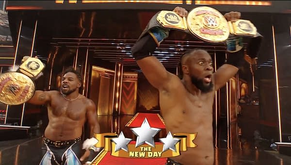 Two wrestlers from The New Day celebrate after winning the tag team titles, holding championship belts high with visible excitement in a brightly lit arena during WrestleMania 41.