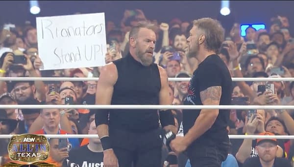 Two wrestlers, Cope and Christian Cage, face each other in a wrestling ring at AEW All In Texas, with a cheering crowd in the background. A sign in the audience reads "Rianators Stand UP!"