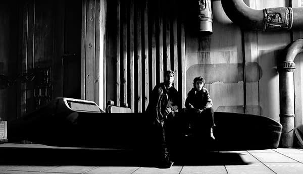 A black and white photograph featuring actors Ryan Gosling and Flynn Gray on the set of 'STAR WARS: STARFIGHTER', seated on a sleek starfighter model against an industrial backdrop.