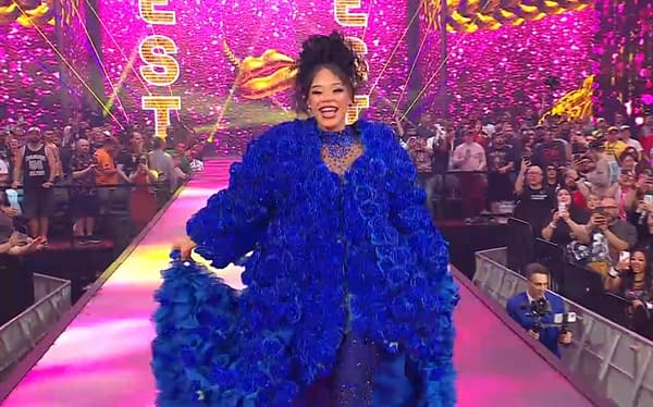 A joyful woman walks down a brightly lit runway, wearing a striking blue floral coat and surrounded by a cheering crowd. The background features colorful lights and decorations, creating a festive atmosphere.