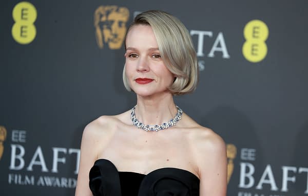A portrait of actress Carey Mulligan at the BAFTA Film Awards, wearing a black strapless dress and a sparkling necklace, with a neutral background featuring BAFTA logos.