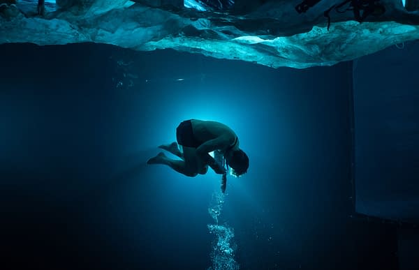 A dramatic underwater scene from 'Mission: Impossible - The Final Reckoning', featuring a swimmer in mid-air, surrounded by blue light and bubbles as they prepare for a dive.
