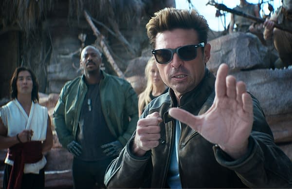 A scene from 'Mortal Kombat 2' featuring a group of diverse characters, with one man in the foreground wearing sunglasses and striking a fighting pose, while others observe in the background.