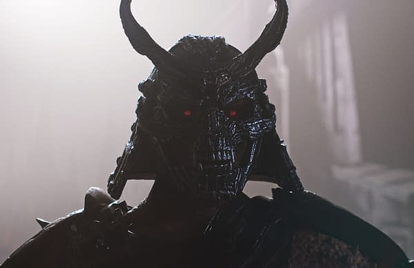 A dark, menacing warrior wearing a heavily designed helmet with horns and glowing red eyes, showcasing an imposing presence in a misty environment, typical of the Mortal Kombat franchise.