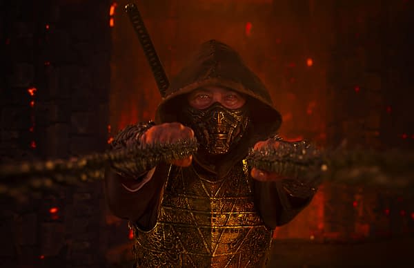A character from Mortal Kombat II is featured, dressed in a dark hood and intricate golden armor, extending a weapon toward the viewer. The background is a dramatic setting infused with glowing red light, enhancing the intense atmosphere.