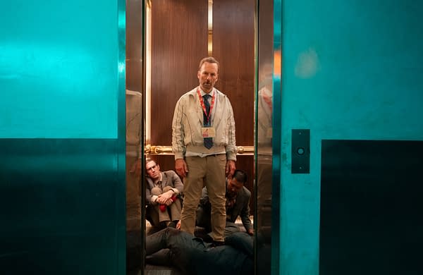 A scene from 'Nobody 2' featuring Bob Odenkirk as Hutch Mansell, standing in a dimly lit elevator with a tense expression. Two men are seated on the floor behind him, suggesting a chaotic or intense situation.