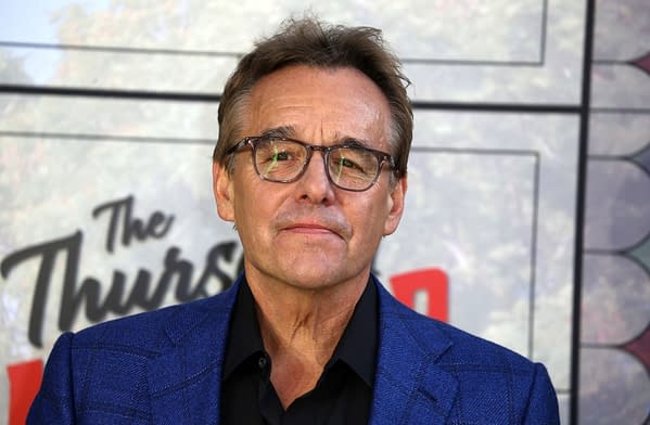 American director Chris Columbus is seen in a close-up portrait, wearing glasses and a blue blazer, at a premiere event in London. The background features text related to the event.