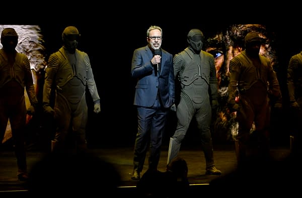 Denis Villeneuve speaks onstage at CinemaCon 2026 with masked Dune characters standing around him.