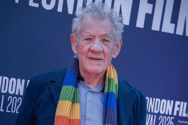 Ian McKellen poses on the red carpet at a London Film Festival event, wearing a colorful striped scarf and dark jacket.