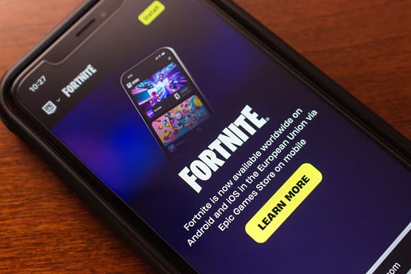 A smartphone displaying the Fortnite app with promotional text indicating its availability on Android and iOS platforms, against a dark background.