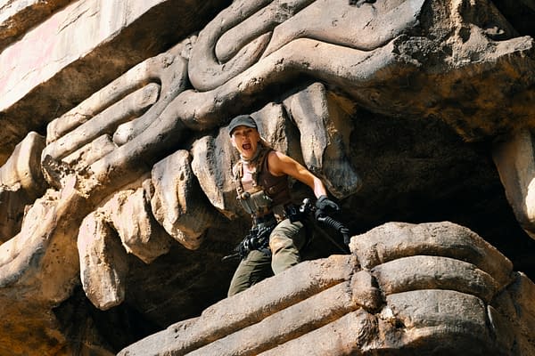 Scarlett Johansson portrays Zora Bennett, a covert operations expert, in a dramatic scene from Jurassic World Rebirth, featuring her shouting while positioned on an ancient stone structure.
