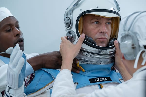 In a scene from 'The Fantastic Four: First Steps,' Ebon Moss-Bachrach portrays Ben Grimm/The Thing as he is assisted by crew members in putting on a space suit helmet in a futuristic setting.