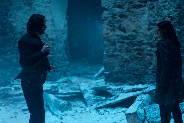 A scene from the film 'Ballerina' featuring Keanu Reeves as John Wick confronting Ana de Armas as Eve in a snow-covered, damaged environment with visible debris.