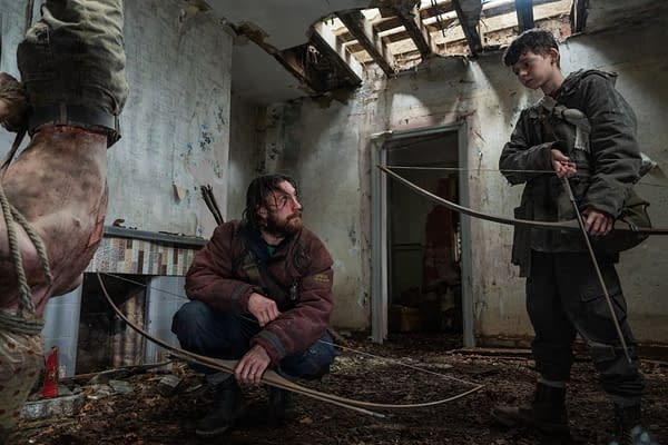 A dramatic scene in a dilapidated room where a rugged man and a young boy are preparing to use bows and arrows. The setting is dark and gritty, suggesting a tense atmosphere.