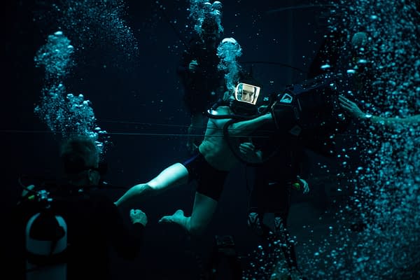 A scene from 'Mission: Impossible - The Final Reckoning' shows a diver in an underwater setting, wearing a helmet and interacting with filming equipment, surrounded by bubbles and other divers.