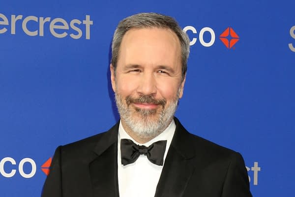 A man with a beard, wearing a tuxedo with a bow tie, smiles in front of a blue backdrop featuring the text 'silvercrest' and a logo. The setting appears elegant, suggesting a formal event.