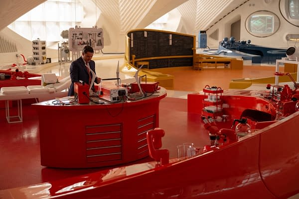 A scene from 'The Fantastic Four: First Steps' features Pedro Pascal as Reed Richards/Mister Fantastic in a sleek, modern lab filled with red and white futuristic equipment.