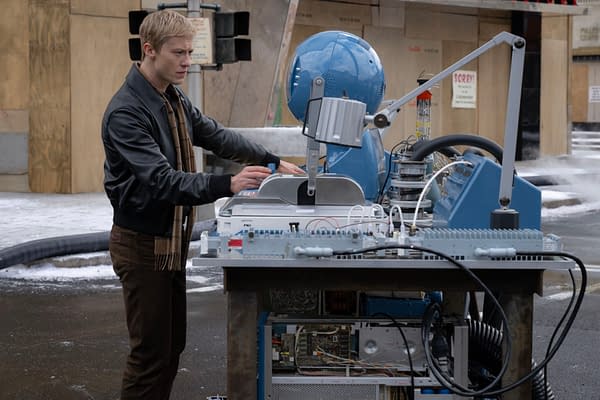 Scene from 'The Fantastic Four: First Steps' featuring Joseph Quinn as Johnny Storm/Human Torch, interacting with a futuristic control device on a street set, surrounded by construction and snowy ground.