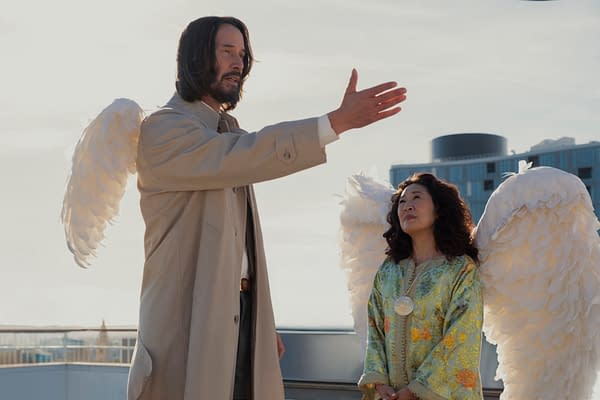 Keanu Reeves and Sandra Oh as angelic characters in the film 'Good Fortune,' with Reeves extending his arm and Oh looking contemplatively ahead. Both characters are dressed in flowing garments and adorned with large, feathered wings.