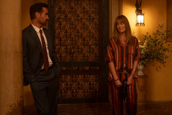 A scene featuring two characters engaged in conversation; one is a man in a suit leaning against a column, while the other is a woman in a striped outfit with an umbrella, standing nearby. The background includes an ornate metal gate and soft lighting, contributing to a warm ambiance.
