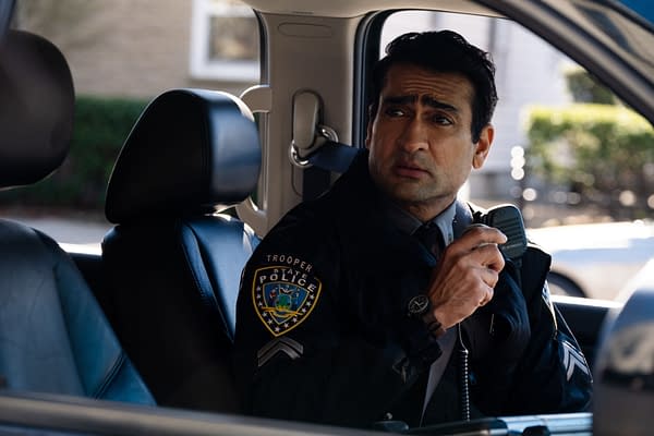 Kumail Nanjiani as Trooper Nash in a police vehicle, speaking into a microphone, wearing a uniform with a trooper badge from 20th Century Studios' ELLA MCCAY.