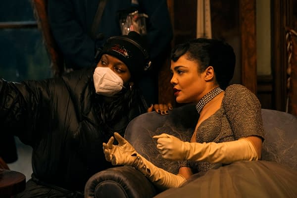 Director Nia DaCosta and actress Tessa Thompson collaborate on the set of 'Hedda,' with Thompson dressed in elegant attire and gloves, deep in conversation.