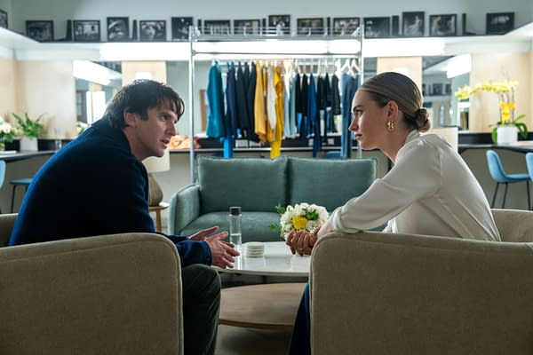 Dan Stevens as Andrey and Lily James as Whitney Wolfe Herd sit in a modern interior, engaged in a serious conversation across a coffee table, surrounded by clothing racks. This scene is from the film SWIPED.