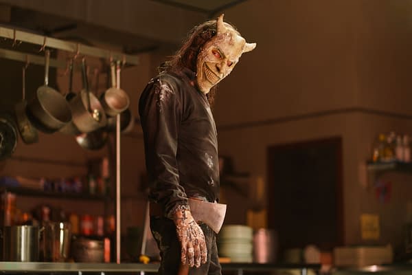 Ethan Hawke portrays The Grabber in Black Phone 2, wearing a menacing mask and holding an axe, set in a dimly lit kitchen environment.