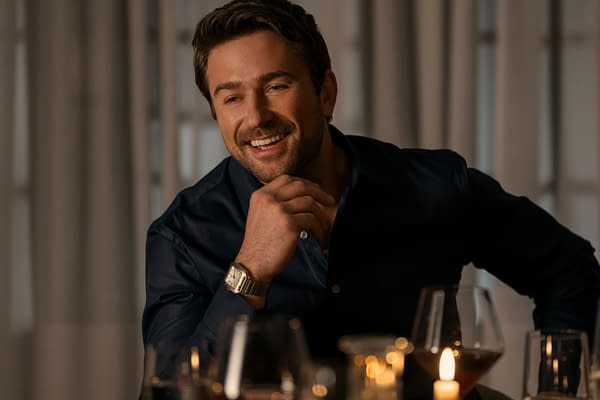 Brandon Sklenar as Andrew Winchester in The Housemaid, smiling warmly during a dinner setting, surrounded by candles and glasses.