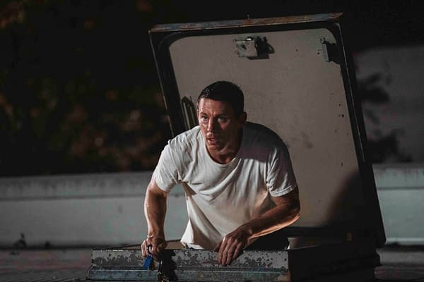 Channing Tatum appears in a tense moment as he emerges from a rooftop access hatch, wearing a plain white t-shirt and holding a set of keys.