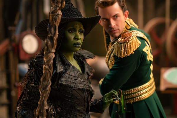 Cynthia Erivo as Elphaba, featuring green skin and a dramatic black costume, stands beside Jonathan Bailey as Fiyero, dressed in a green uniform adorned with gold embellishments, in a scene from "Wicked: For Good" directed by Jon M. Chu.